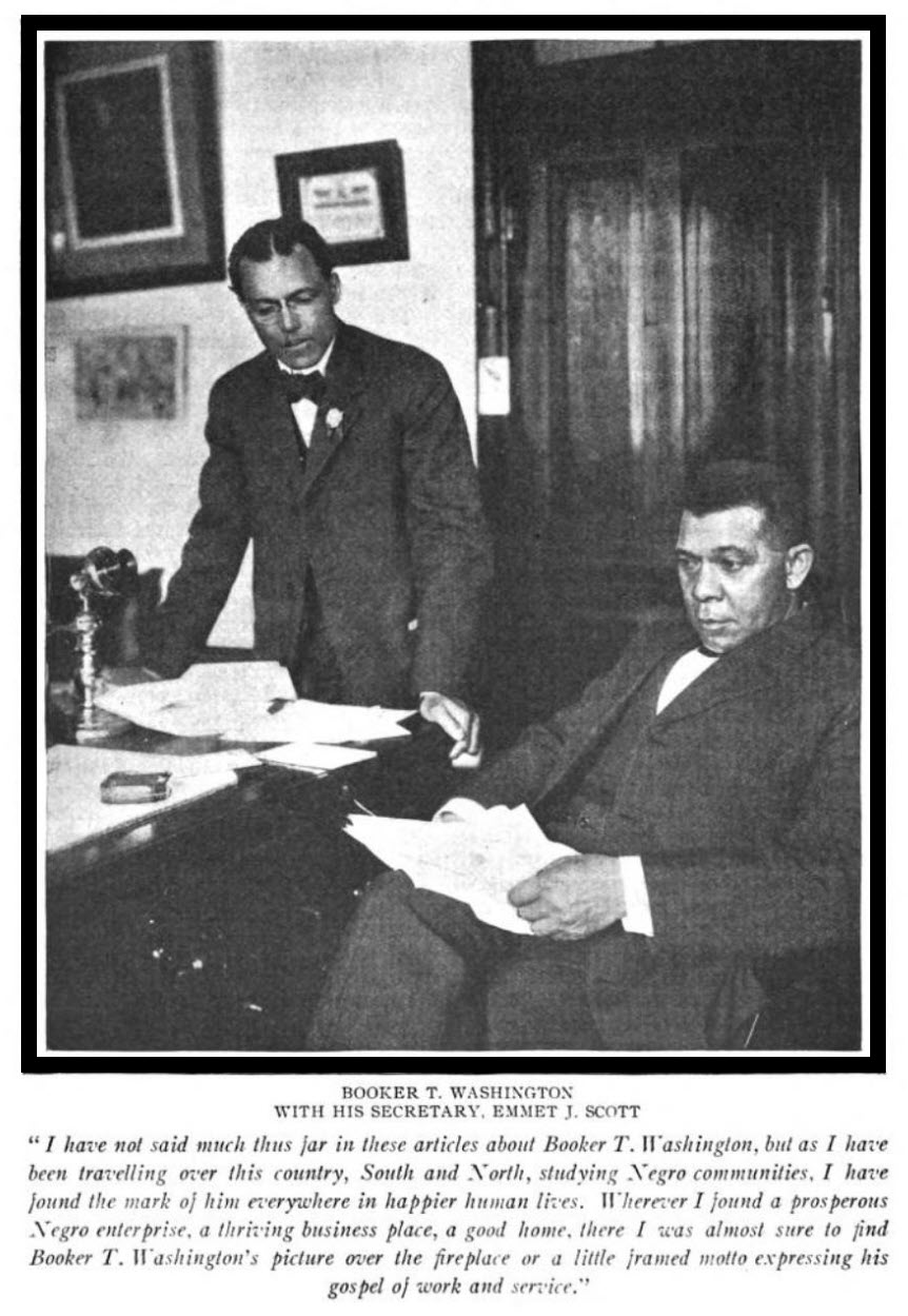 Picture of Booker T. Washington sitting at his desk with his secretary, Emmet J. Scott at his side.