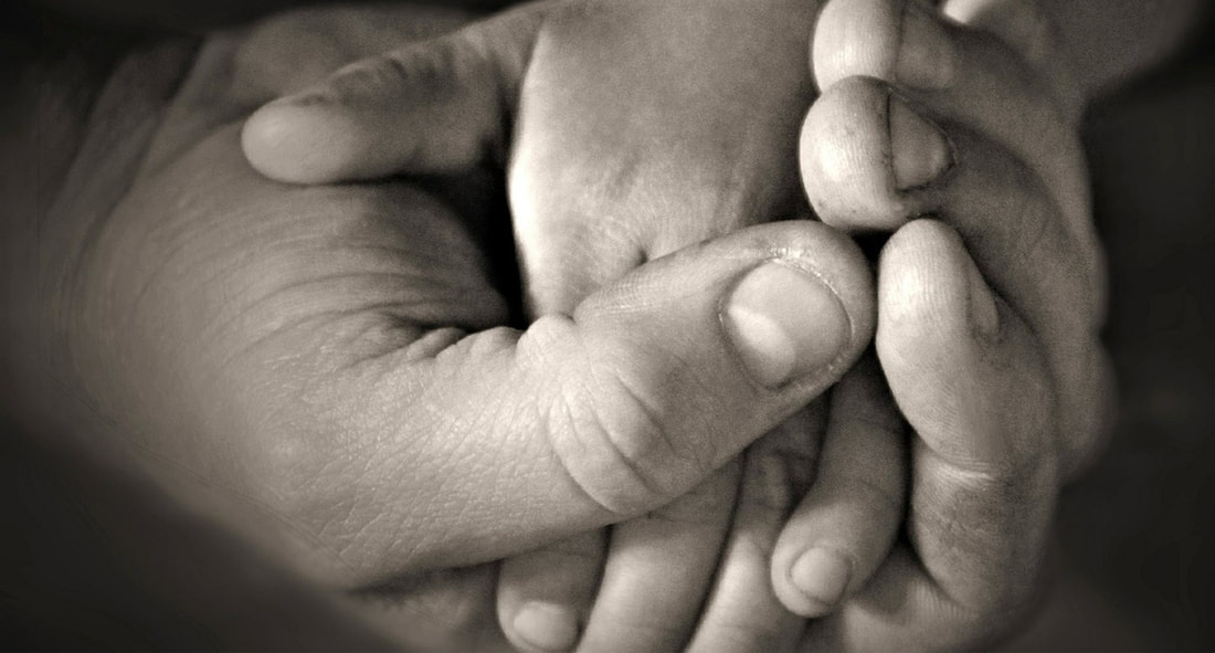 Image of an adult's hand holding a child's hand.