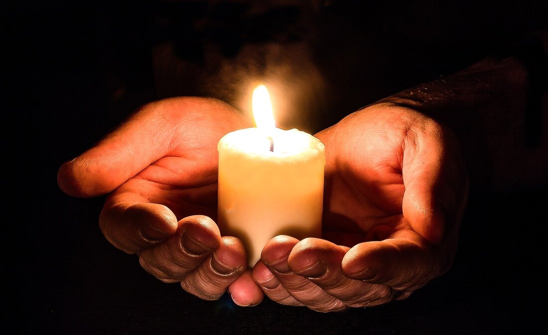 Picture of hands cradling a lit candle.